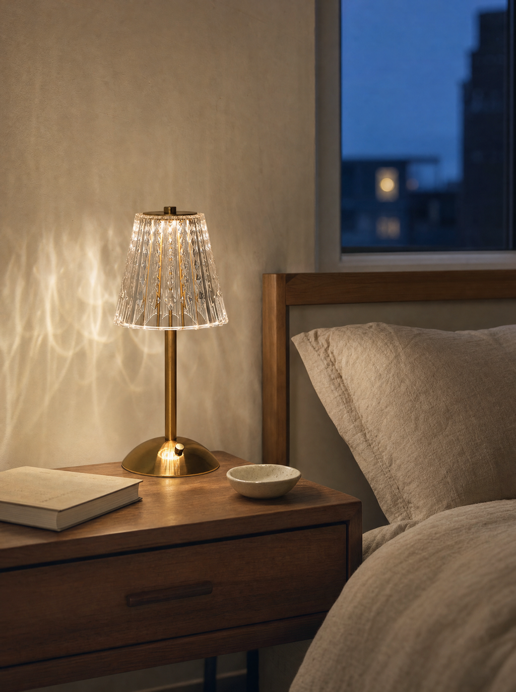Cordless crystal-cut table lamp with fluted cone shade on a nightstand