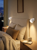 Two stick-on rechargeable wall sconces on both sides of a bed in a rental bedroom