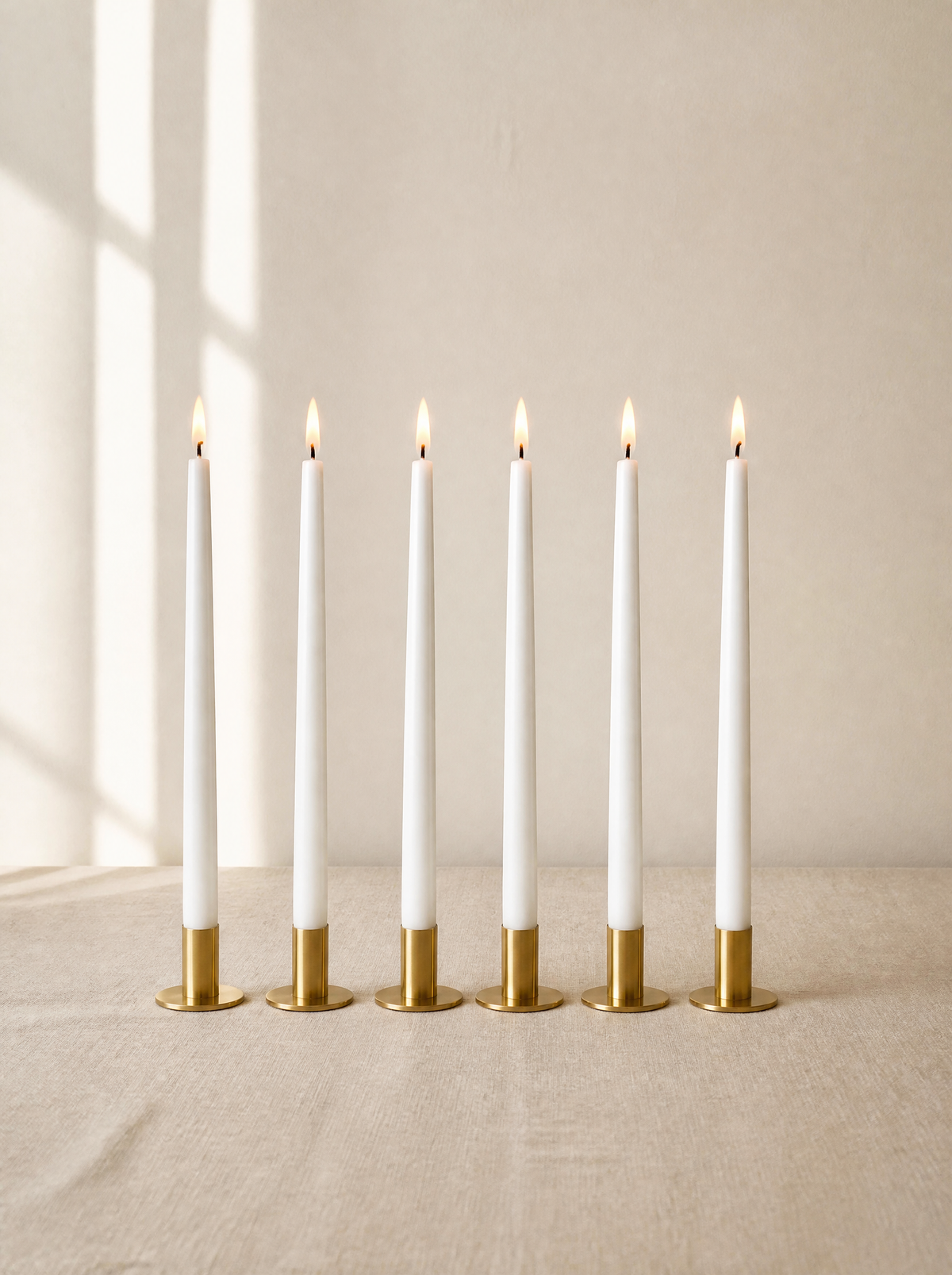 Six white flameless taper candles in brass holders, daylight