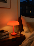 Orange cordless mushroom lamp on a walnut nightstand