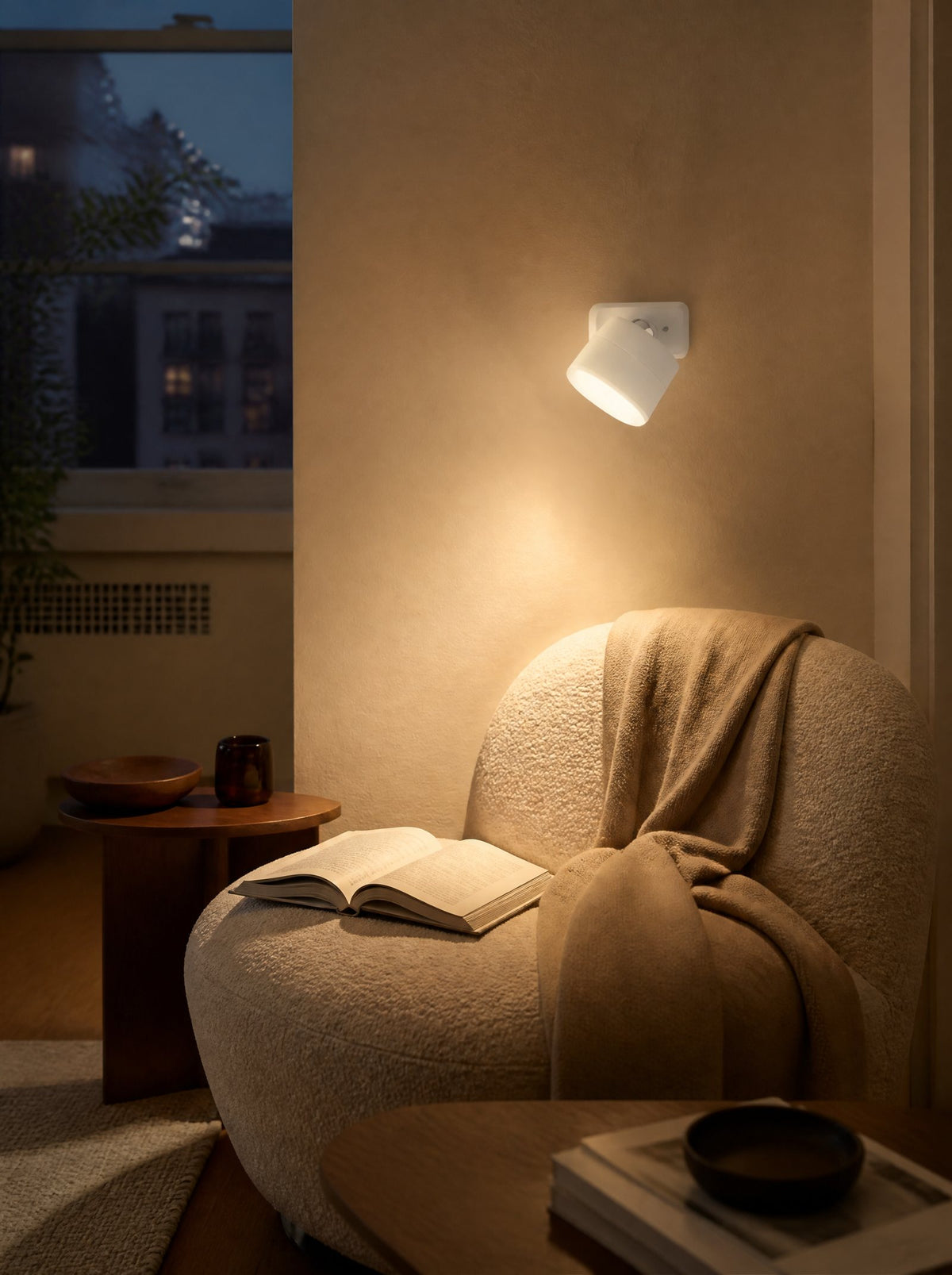 A stick-on wall light glowing above an armchair in a dark living room